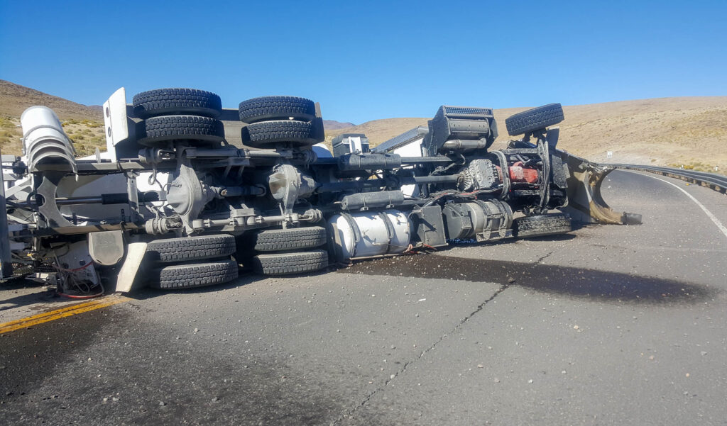 Crashed cement or concrete truck on its side on a roadway.